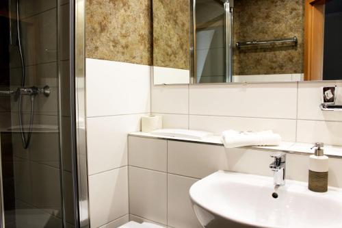 uma casa de banho branca com um lavatório e um chuveiro em Hotel Sächsisches Haus em Berggiesshübel
