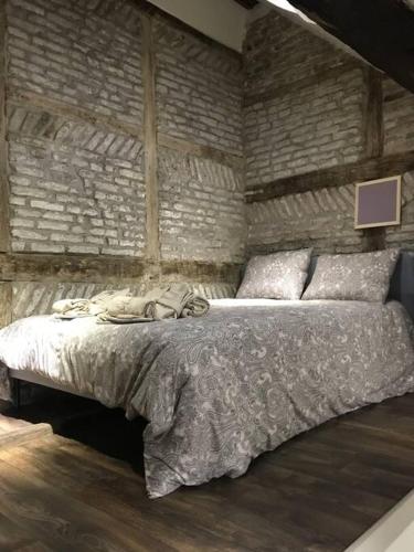 uma cama num quarto com uma parede de tijolos em Petite maison Liégeoise «la cabane de Liège» em Liège