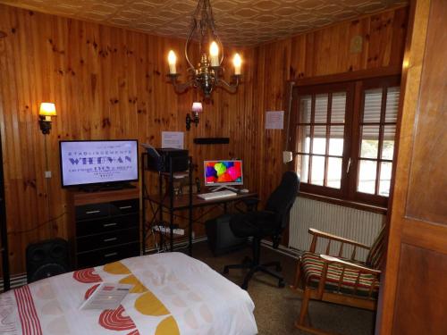 a bedroom with a bed and a television and a desk at Chambre d'hôte in Allouagne