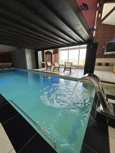 une grande piscine avec une fontaine dans l'établissement Centre de bien-être Le Miel et l'Eau, à Clermont-Dessous