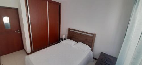 um pequeno quarto com uma cama e uma cabeceira em madeira em Apartamento Santos em Ribeira Grande