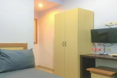 1 dormitorio con 1 cama y armario con TV en OYO 93169 Bnb Homestay en Parepare