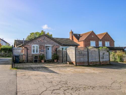 a brick house with a fence in front of it at Virginia Cottage in Acton Burnell