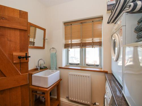 a bathroom with a sink and a washing machine at Virginia Cottage in Acton Burnell