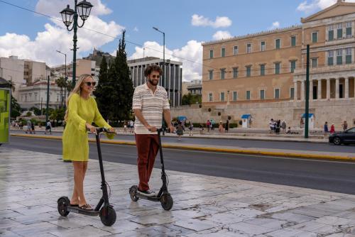 a man and a woman riding on scooters on a street at Hestia - Averof 7 in Athens