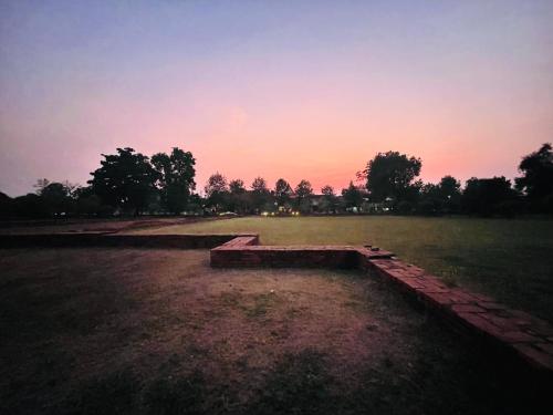 a bench in a field with a sunset in the background at Baan Lhang Wangh บ้านหลังวัง in Phitsanulok