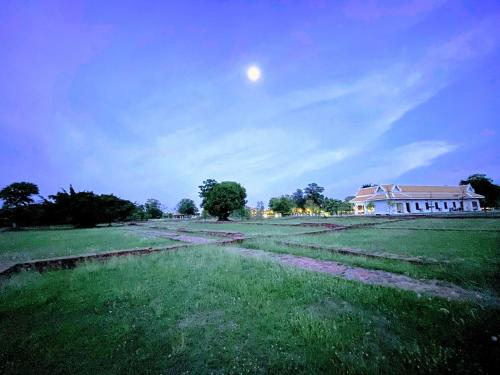 a house in a field with the moon in the sky at Baan Lhang Wangh บ้านหลังวัง in Phitsanulok