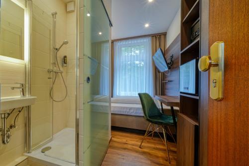 ein Bad mit einer Dusche und einem Waschbecken sowie einen Schreibtisch in der Unterkunft Zentrum Hotel Stade in Stade