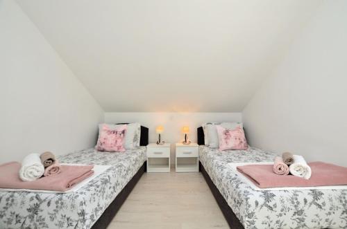 - 2 lits dans une chambre de couleur rose et blanche dans l'établissement Apartments Viktoria, à Lovran