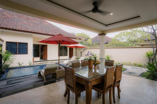 a dining room with a table and chairs and a pool at Ombak Sunset in Gili Trawangan