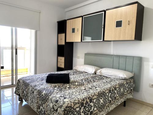 a bedroom with a bed with a black bag on it at Apartamentos Medano - La Ladera in El Médano