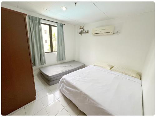 a small bedroom with a bed and a window at Sea & Wave #1 Coral Bay Apartment in Pangkor