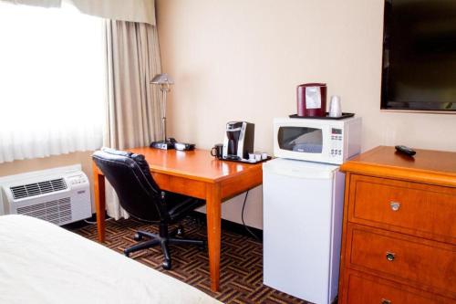 a hotel room with a desk with a microwave and a bed at Wyndham Garden Medicine Hat Conference Center in Medicine Hat