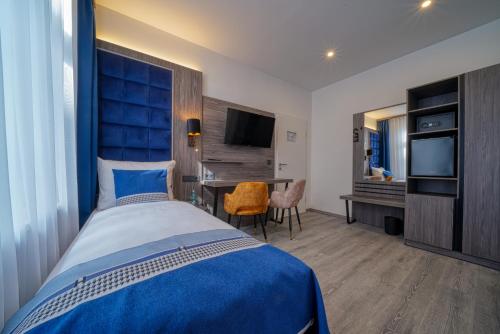 a bedroom with a bed and a desk and a television at Zentrum Hotel Stade in Stade