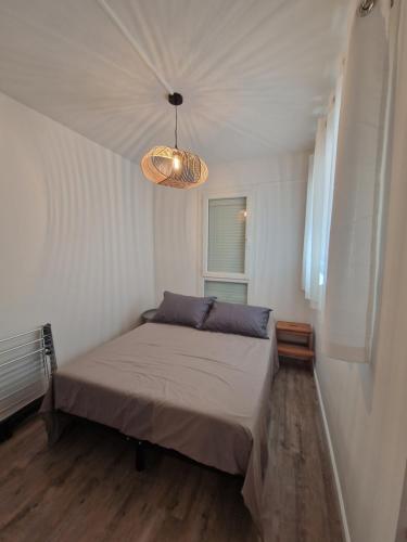 a small bedroom with a bed and a chandelier at T2 Cap d'agde centre port in Cap d'Agde