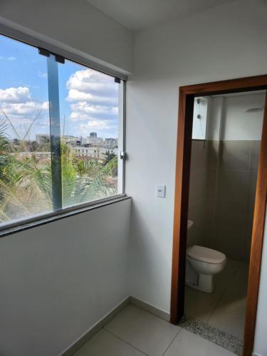 a bathroom with a toilet and a large window at Comfort 302 - 4 Quartos no Centro in Sete Lagoas