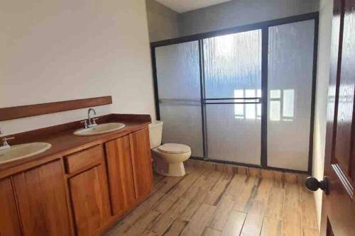 baño con 2 lavabos, aseo y puerta corredera de cristal en Casa del Sol, en Parrita