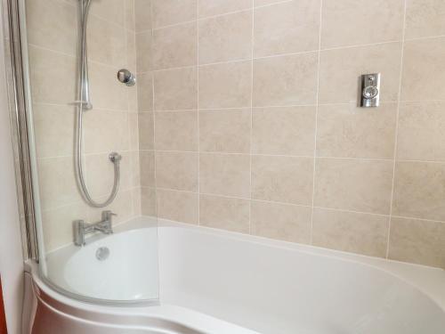 a bathroom with a bath tub with a shower at Seaview Cottage in Holt