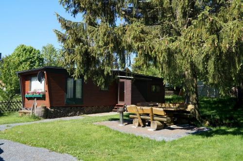 a cabin with a picnic table and chairs under a tree at Kammbaude Neuhermsdorf in Neuhermsdorf
