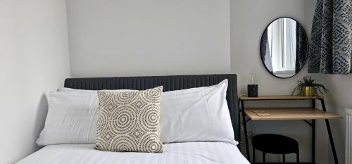 a bed with a pillow and a table with a mirror at Harlequin Apartments by Switchback Stays in Cardiff