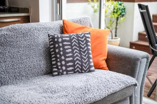 a gray couch with an orange pillow on it at Gorgeous Kentish Town Flat in London