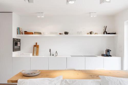 a kitchen with white cabinets and a wooden table at Julias Studio Stay in Knokke-Heist