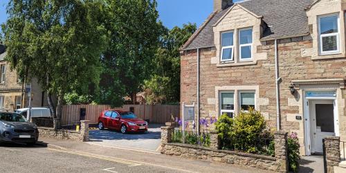 a red car parked in front of a brick house at The Ness Guest House in Inverness