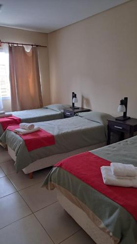 a room with three beds with red and green blankets at Newen Bed and breakfast in El Chalten