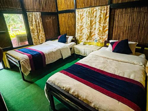 a bedroom with two beds and a window at Hotel Tharu Garden And Beer Bar in Chitwan