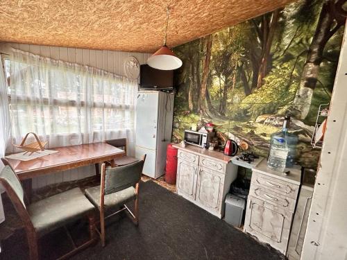 een keuken met een bureau, een tafel en een koelkast bij Piekalne in Kalnieši