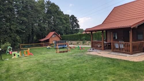 ein großer Hof mit einem Haus mit Spielplatz in der Unterkunft Domki u Jacka in Wilkasy