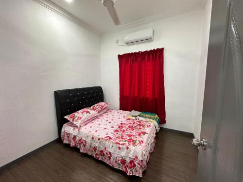 a small bedroom with a bed with a red curtain at Dhia Homestay2 in Macang
