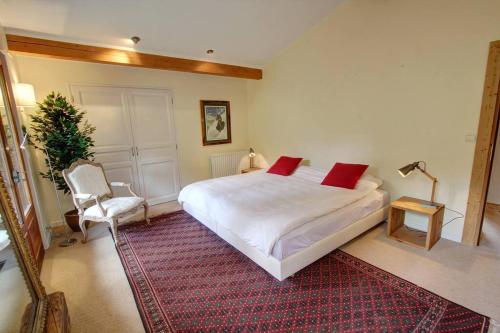 um quarto com uma grande cama branca e uma cadeira em Chalet Clara em Chamonix-Mont-Blanc