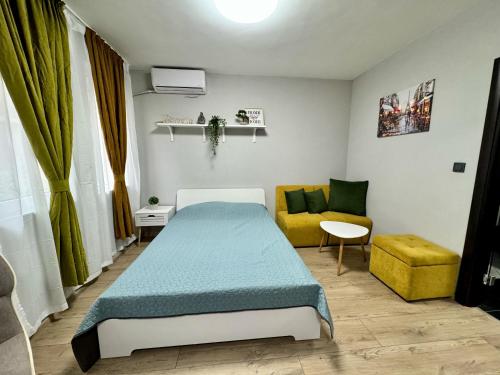 ein Schlafzimmer mit einem Bett und einem gelben Sofa in der Unterkunft Central Studio Apartment - Varna City in Warna