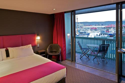 a hotel room with a bed and a balcony with a view at Zero Davey Boutique Apartment Hotel in Hobart