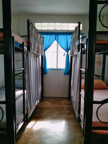 a room with three bunk beds and a window at The Dreamcatcher Hostel Nathon SamuiSunset in Nathon