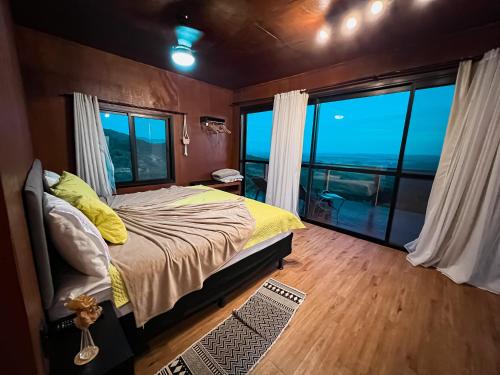 a bedroom with a bed and a large window at Famiglia da Serra in Delfinópolis