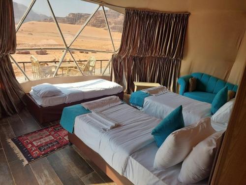 a room with three beds and a view of the desert at Hashem desert camp in Wadi Rum
