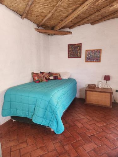- une chambre avec un lit bleu dans un mur blanc dans l'établissement Cabaña Pimientos, à San Pedro de Atacama