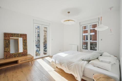 een witte slaapkamer met een bed en een spiegel bij Maison moderne parisienne in Colombes
