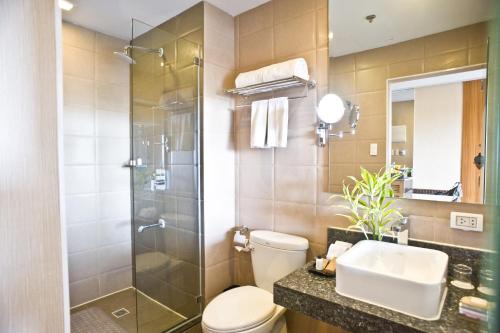 a bathroom with a shower and a toilet and a sink at Goldberry Suites and Hotel - Mactan in Mactan