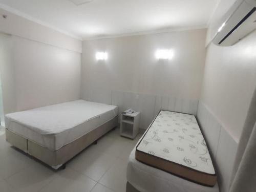 een kleine witte kamer met 2 bedden en een tafel bij Spazzio DiRoma com Parque incluso! in Caldas Novas