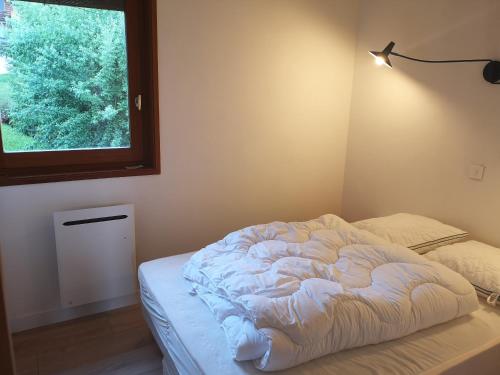an unmade bed in a room with a window at Appartement lumineux, 4-6 personnes, refait à neuf in Les Gets