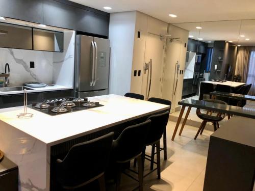 uma cozinha com um fogão e um balcão com cadeiras em Apartamento moderno em João Pessoa