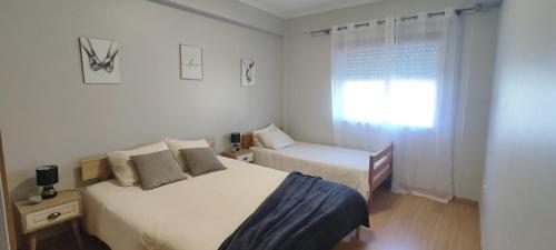 a white bedroom with two beds and a window at Rés do Chão da Montanha Mágica in Lousã
