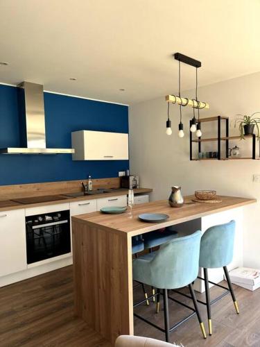 a kitchen with a wooden island with two blue chairs at Pavillon d'Éole in Berck-sur-Mer