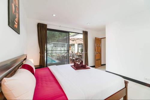 a bedroom with a large white bed and a balcony at Eden villas in Nathon Bay