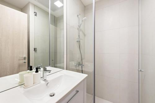 uma casa de banho branca com um lavatório e um chuveiro em VayK - Chic Studio with a Large Terrace in JVC em Dubai