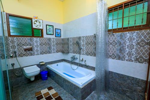 a bathroom with a tub and a toilet at Bay Homes 2BHK WT Bathtub Near Rock Beach in Puducherry