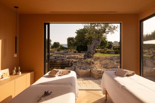 two beds in a room with a large window at Masseria San Francesco in Savelletri di Fasano